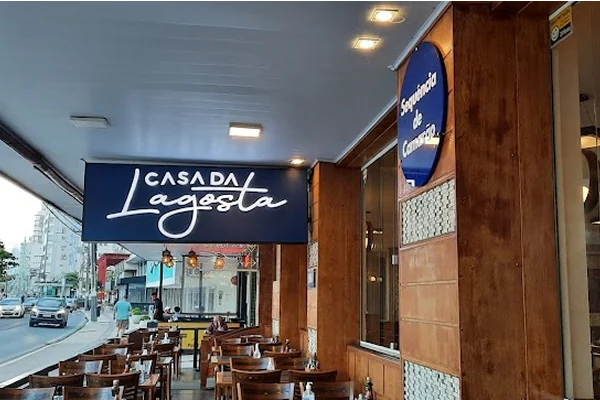 Entrada do restaurante Casa da Lagosta, com mesas dispostas ao ar livre e iluminação aconchegante.