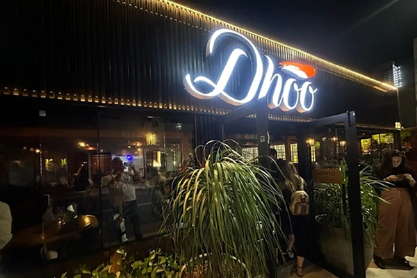 Fachada iluminada do restaurante japonês Dhoo, com letreiro estilizado e ambiente moderno.
