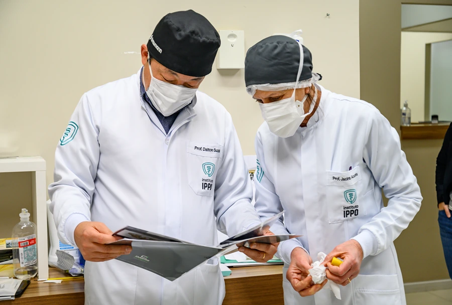 Professores Dalton Suzuki e Jacir Júnior, do Instituto IPPO, revisando materiais de estudo e discutindo tópicos da especialização em implantodontia.