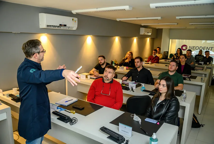 Um instrutor faz uma apresentação para alunos em uma sala de aula equipada no Instituto IPPO, com participantes atentos ao conteúdo.