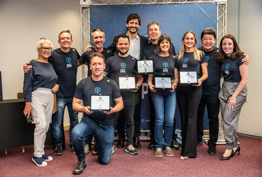 Grupo de instrutores do Instituto IPPO posando com placas de reconhecimento em um evento comemorativo.
