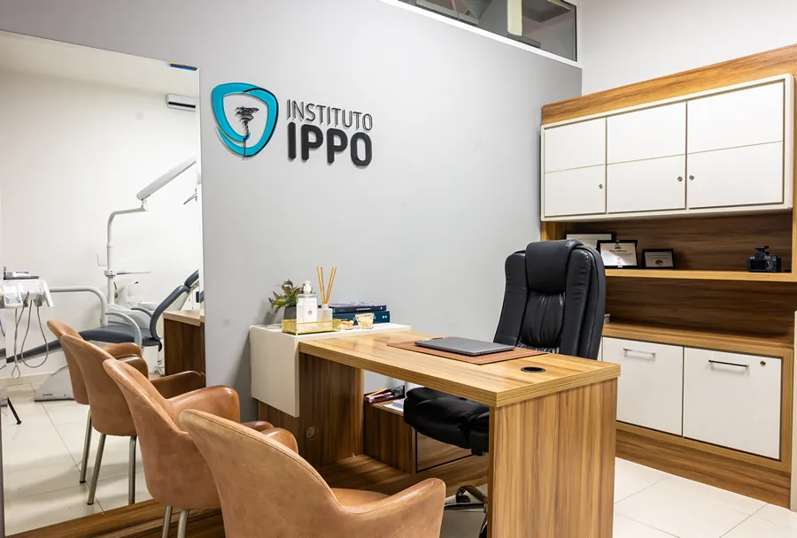 Escritório de atendimento do Instituto IPPO, com uma mesa de madeira, cadeiras confortáveis e o logotipo do instituto na parede.